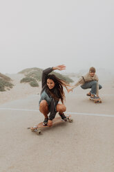 Junges Paar beim Skateboarden auf einem nebligen Strandparkplatz, Jalama, Kalifornien, USA - ISF20552