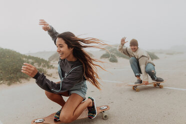 Junges Paar beim Skateboarden auf einem nebligen Strandparkplatz, Jalama, Kalifornien, USA - ISF20553