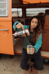Junge Frau gießt Kaffee bei einem Wohnmobil ein, Jalama, Kalifornien, USA - ISF20555
