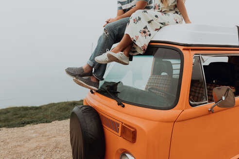Young couple on top of recreational vehicle at coastal roadside, cropped, Jalama, California, USA - ISF20557