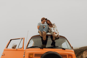 Young couple sitting on top of recreational vehicle, Jalama, California, USA - ISF20558