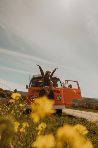 Junge Frau sitzt vor einem Wohnmobil an einer Landstraße, Jalama, Kalifornien, USA, lizenzfreies Stockfoto