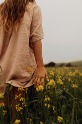 Young woman walking in yellow wildflower field, rear view, Jalama, California, USA - ISF20576