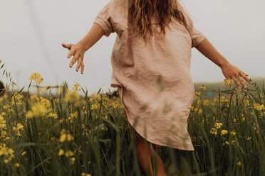 Junge Frau, die in einem gelben Wildblumenfeld spazieren geht, Rückansicht, Jalama, Kalifornien, USA - ISF20577