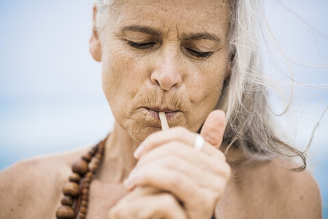 Porträt einer älteren Hippie-Frau, die im Freien raucht, lizenzfreies Stockfoto