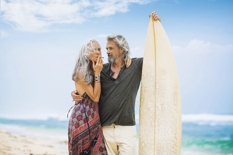 Senior hippie couple with surfboard on the beach stock photo