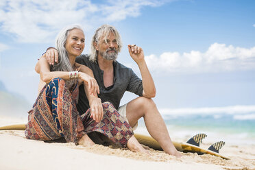 Porträt eines älteren Hippie-Paares mit Surfbrett, das sich am Strand entspannt - SBOF01709