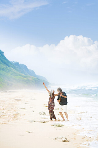 Glückliches älteres Hippie-Paar mit Gitarre beim Tanzen am Strand, lizenzfreies Stockfoto