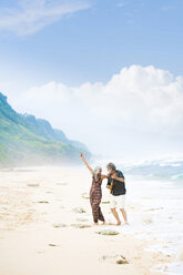 Glückliches älteres Hippie-Paar mit Gitarre beim Tanzen am Strand - SBOF01713