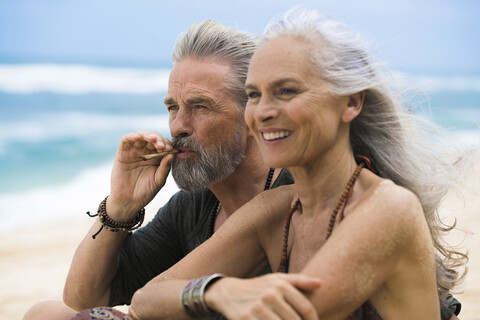 Senior hippie couple relaxing together on the beach stock photo