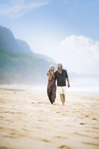 Senior hippie couple strolling together on the beach stock photo