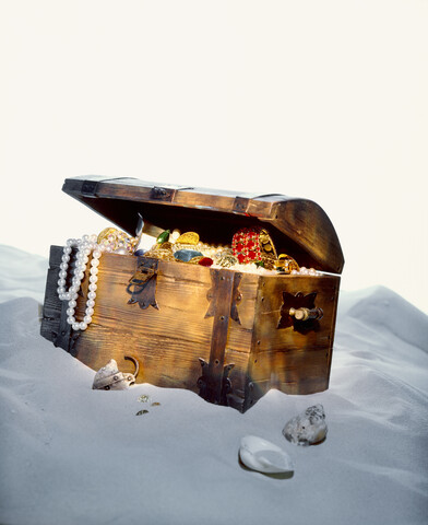 Mit Juwelen gefüllte Schatztruhe am Sandstrand, lizenzfreies Stockfoto