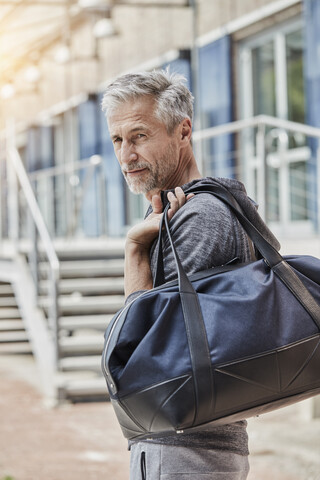 Portrait of mature man with sports bag standing in front of gym stock photo