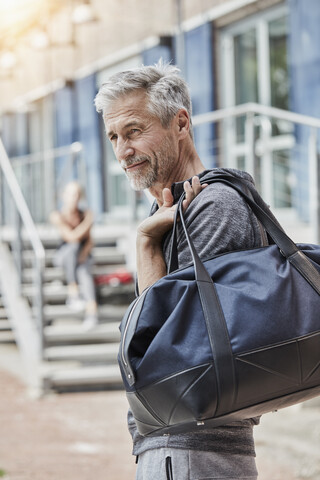 Porträt eines reifen Mannes mit Sporttasche, der vor einem Fitnessstudio steht, lizenzfreies Stockfoto