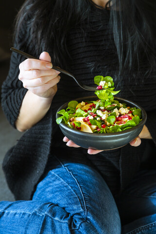 Frau isst gemischten Salat mit Feldsalat, Feta, Birne, Granatapfelkernen und Walnüssen, lizenzfreies Stockfoto