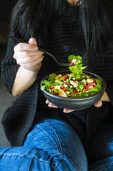 Frau isst gemischten Salat mit Feldsalat, Feta, Birne, Granatapfelkernen und Walnüssen - SARF04106