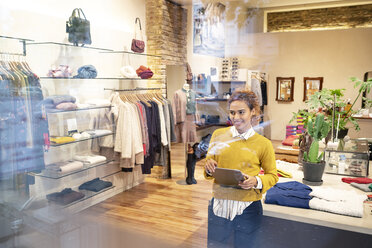 Young woman working in fashion store, using laptop - PESF01375