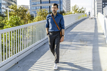 Portrait of businessman walking on footbridge - GIOF05724