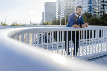 Man leaning on railing of footbridge looking at distance - GIOF05732