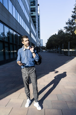 Porträt eines Mannes mit Kopfhörern und Mobiltelefon, lizenzfreies Stockfoto