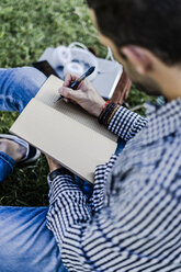 Man sitting on a meadow taking notes - GIOF05750