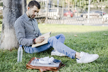 Man sitting on a meadow taking notes - GIOF05752