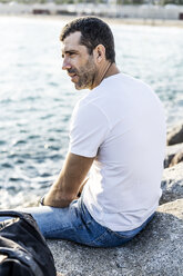 Man sitting on a rock in front of the sea relaxing - GIOF05766