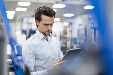 Porträt eines Geschäftsmannes, der ein Tablet in einer Fabrik benutzt - DIGF05654