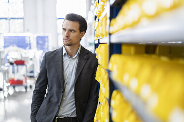 Businessman in storehouse of a factory looking around - DIGF05672