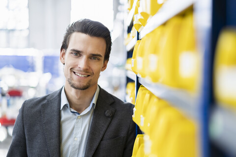 Porträt eines lächelnden Geschäftsmannes in einem Lagerhaus einer Fabrik, lizenzfreies Stockfoto