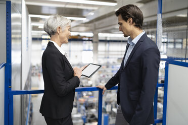 Businessman and senior businesswoman with tablet talking in a factory - DIGF05680