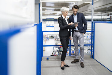 Businessman and senior businesswoman with tablet talking in a factory - DIGF05684