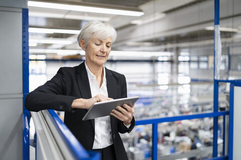 Ältere Geschäftsfrau mit Tablet in einer Fabrik, lizenzfreies Stockfoto