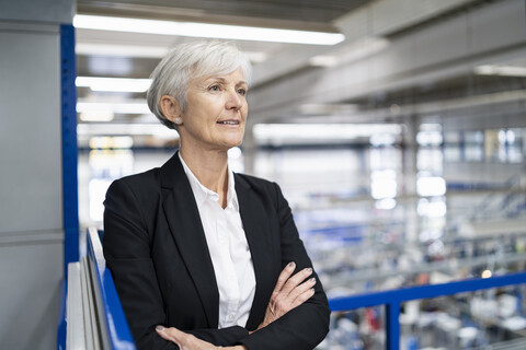 Selbstbewusste ältere Geschäftsfrau in einer Fabrik, die sich umschaut, lizenzfreies Stockfoto