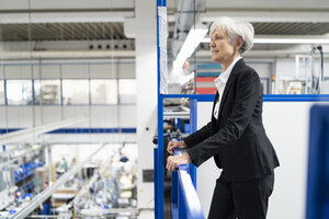 Ältere Geschäftsfrau im Obergeschoss einer Fabrik mit Blick auf den Verkaufsraum - DIGF05698