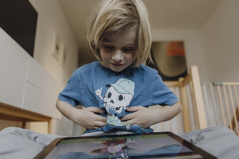 Porträt eines zufriedenen kleinen Jungen, der zu Hause ein digitales Tablet benutzt, lizenzfreies Stockfoto
