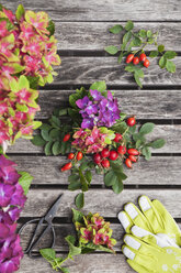 Hydrangeas and rosehips, gardening gloves and scissors on garden table - GWF05871