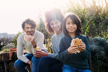 Happy family siting in garden, taking a break, eating sandwiches - GEMF02715