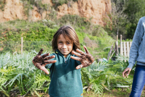 Junge zeigt seine schmutzigen Hände, die voller Erde sind, lizenzfreies Stockfoto
