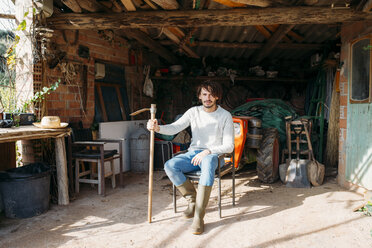 Man with a hoe sitting in a shed with a tractor - GEMF02788