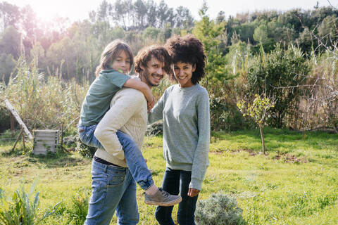 Glückliche Familie beim Spaziergang auf dem Land, Vater trägt Sohn huckepack, lizenzfreies Stockfoto