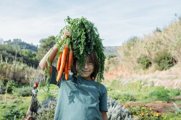 Boy standing in vegetable garden, holding a bunch of carrots - GEMF02831