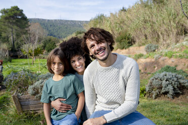 Glückliche Familie, die auf einer Bank im Garten sitzt und Spaß in der Natur hat - GEMF02840