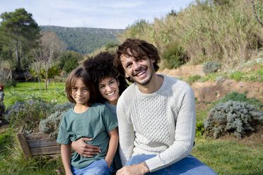 Happy family sitting on a bench in a garden, having fun in the countryside - GEMF02840