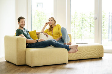 Couple sitting on couch in their new home, discussing - PESF01425