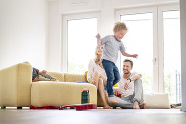 Glückliche Familie beim Einzug in ihr neues Haus, Junge springt von der Couch - PESF01443