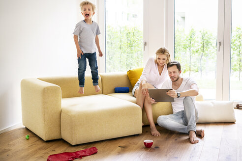 Glückliche Familie beim Einzug in ihr neues Haus, Junge springt auf der Couch herum - PESF01445