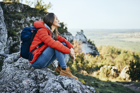 Frau bei einer Wanderung in den Bergen, die sich auf einem Felsen ausruht, lizenzfreies Stockfoto