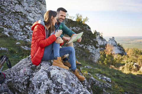 Happy couple on a hiking trip in the mountains taking a break looking at map stock photo