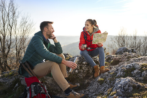 Glückliches Paar auf einem Wanderausflug in den Bergen, das eine Pause macht, lizenzfreies Stockfoto